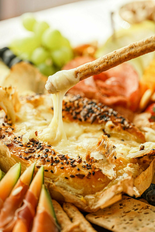Creative Cooking – Cheese (Sir) Cheesy bread with melted cheese oozing out, surrounded by fruits and meats on a plate.