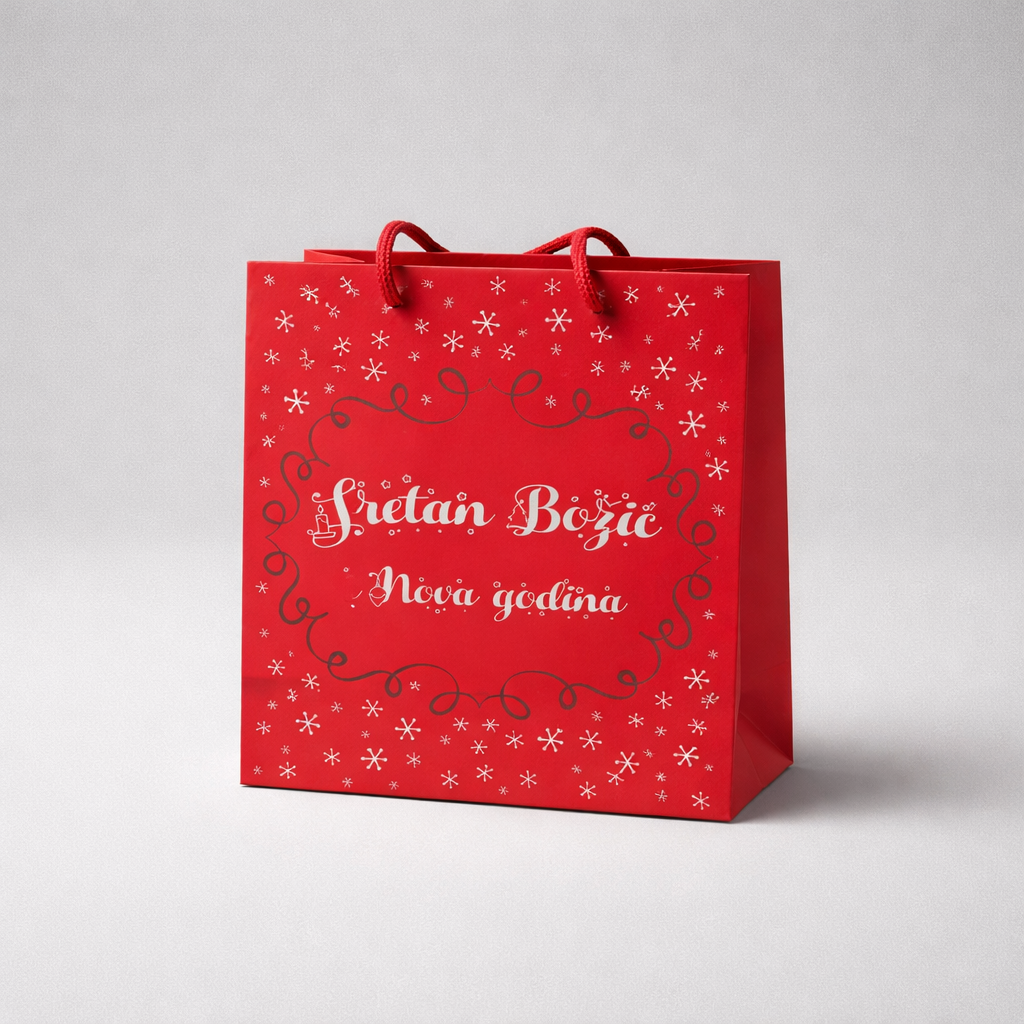 Festive Gift Bag – Sretan Božić Red gift bag with white text and snowflake patterns on a light gray background