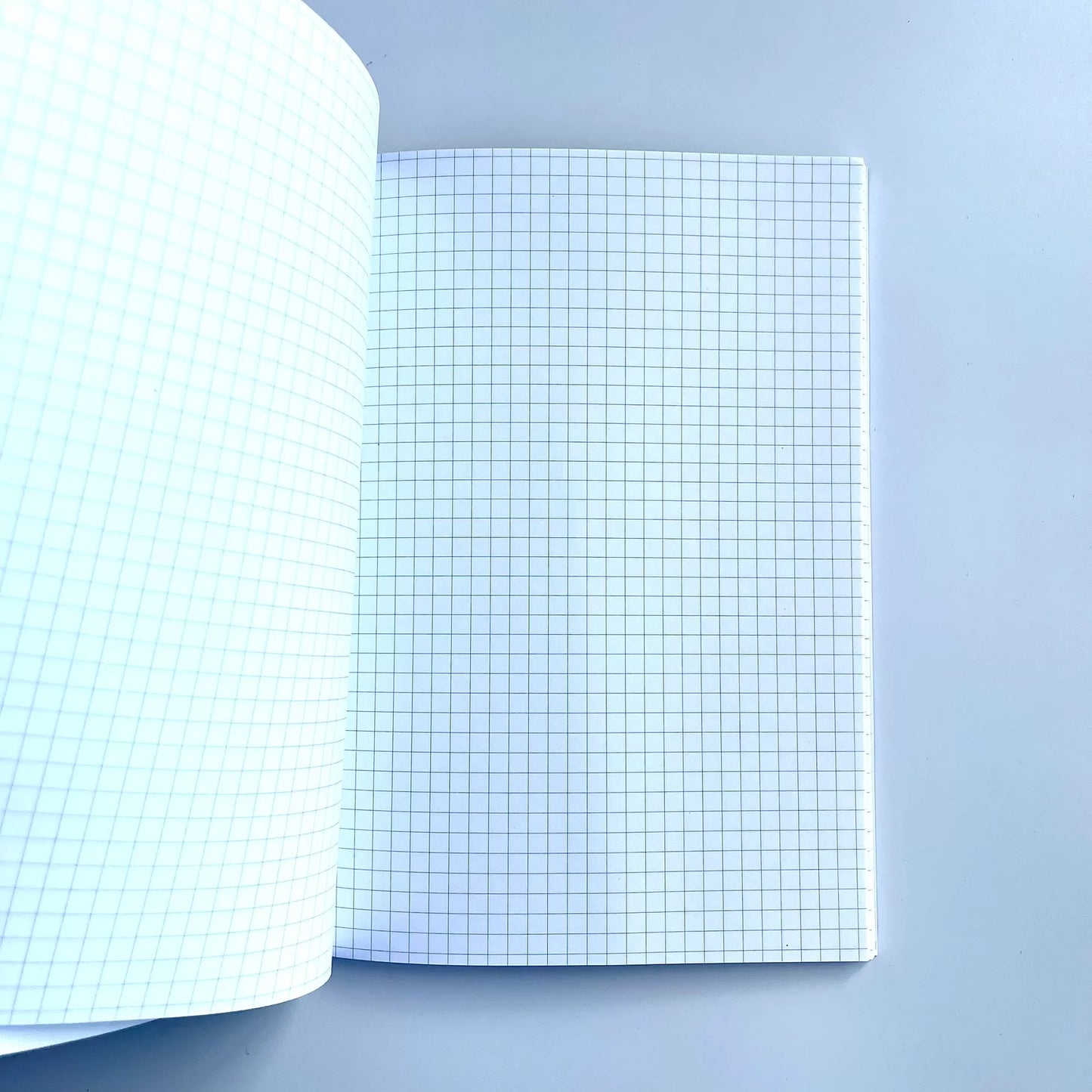 GNK Dinamo A5 Writing Book / Note Pad Open notebook with grid paper on a light blue background