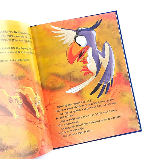 Kralj Lavova by Disney Open book with colorful illustration of a bird on a white background