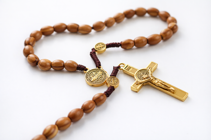 Wooden rosary with gold crucifix and medal on a white background