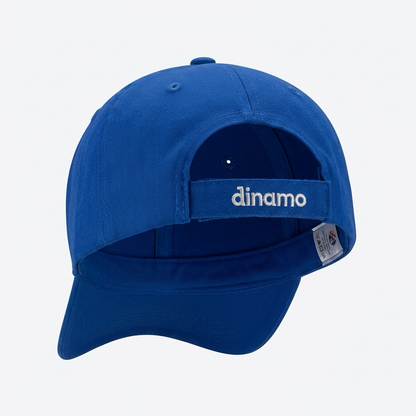 A royal blue baseball cap shown from the back, featuring a curved brim and a hook-and-loop strap closure with the brand name 'dinamo' embroidered in white. A small sewn-in size tag is visible on the side. Baseball Cap Dinamo Zagreb in Blue shopncro
