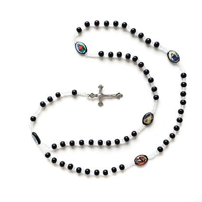 Black & White Catholic Rosary with Religious Medals – Silver Crucifix Black rosary beads with a silver cross on a white background