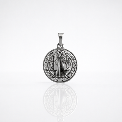 Croatian Medallion Necklace – St. Benedict Catholic Pendant A round silver Saint Benedict medal pendant with an engraved depiction of Saint Benedict and the inscription 'DE OMNIPOTENTE DEI TRINA MAXIMA SENTIA SANCTUS BENEDICTUS', shown on a reflective white surface.