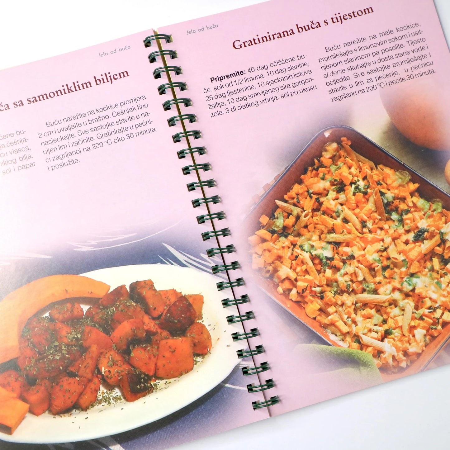 Ekološka Kuharica Open cookbook showing a dish with carrots and pasta on a pink background