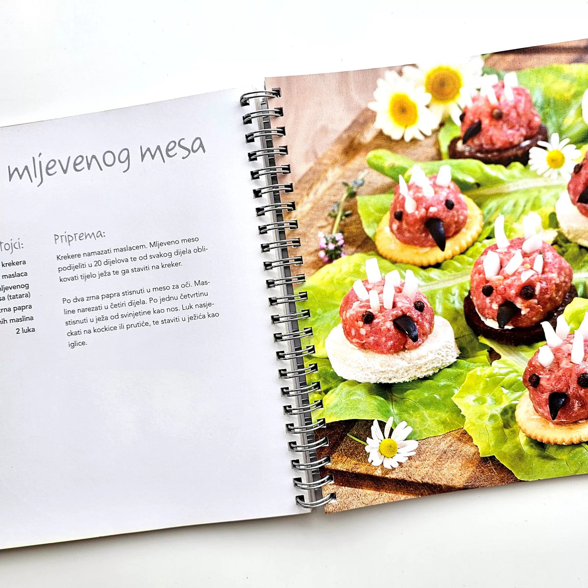 Fingerfood & Zalogajčići Open cookbook showing a recipe for meat skewers on a white surface