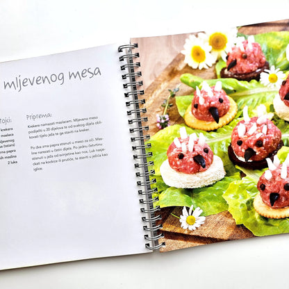 Fingerfood & Zalogajčići Open cookbook showing a recipe for meat skewers on a white surface