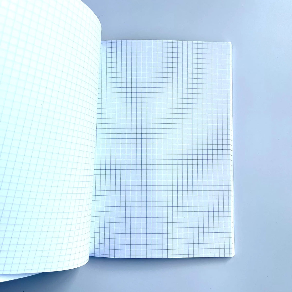 GNK Dinamo A5 Writing Book / Note Pad Open notebook with grid paper on a light blue background