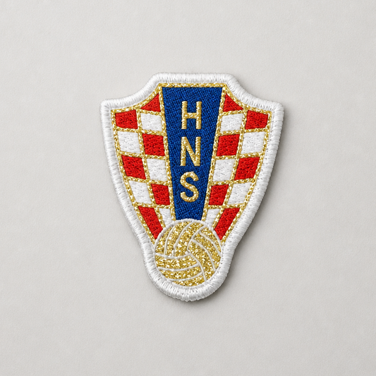 An embroidered shield-shaped patch featuring a red and white checkered pattern, a blue vertical panel with gold 'HNS' lettering, and a gold soccer ball motif at the bottom, set against a plain light gray background. HNS Clothes Patch snc shopncro