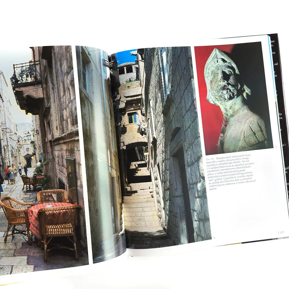 Hrvatska - Photographic Monograph Open book showing images of a narrow street with people, a statue, and a table with chairs.