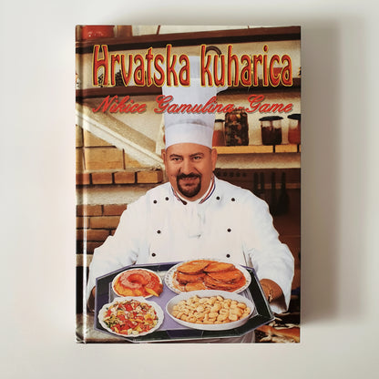Hrvatska Kuharica – Nikica Gamulin Gama Cookbook cover featuring a chef with food on a tray against a kitchen background