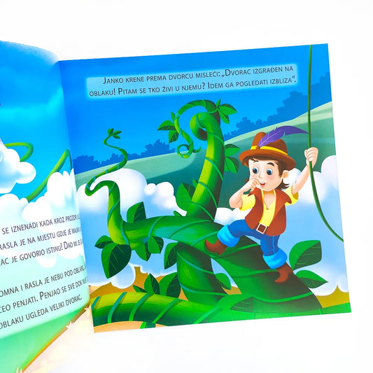 Janko i čarobni Grah Open book with a colorful illustration of a boy climbing a beanstalk, set against a blue sky with clouds.