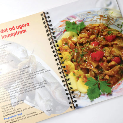 Jela od Ribe Open cookbook with a recipe for a dish featuring meat and vegetables on a white background