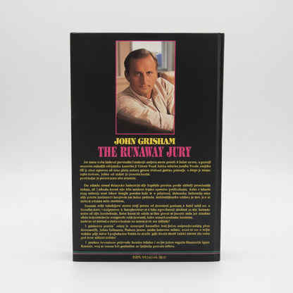 John Grisham - Odmetnuta Porota Book titled 'The Runaway Jury' by John Grisham on a wooden surface with a white wall background.