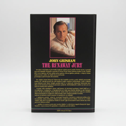 John Grisham - Odmetnuta Porota Book titled 'The Runaway Jury' by John Grisham on a wooden surface with a white wall background.