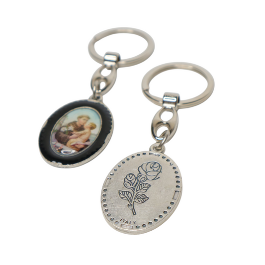 Keyring Saint Anthony of Padua – Double-Sided Religious Medal (Black Enamel) Keychain with circular pendant featuring a rose design and another pendant with an image of a woman.