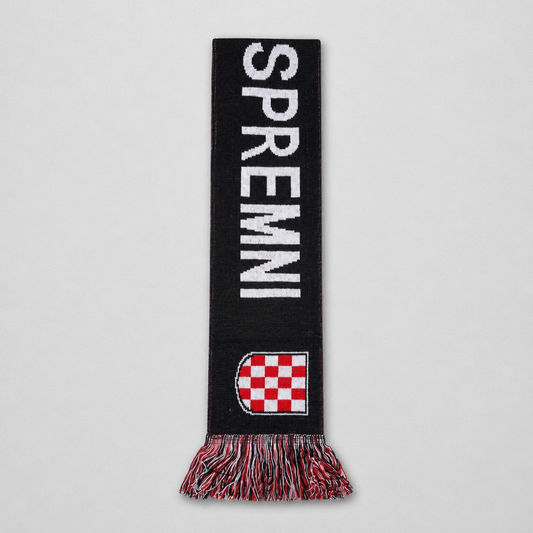 A black knit scarf with 'SPREMI' in bold white letters, a red and white checkered shield near the bottom, and multicolor fringe, shown flat against a light gray background. Knitted Scarf HOS Za Dom Spremni shopncro.live