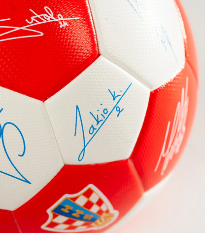 Red and white soccer ball with signatures on a light gray background
