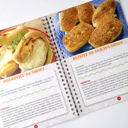 NAJBOLJI DOMAĆI KOLAČI 2 Open cookbook showing a recipe for potkovic with images of bread and cheese on a white background