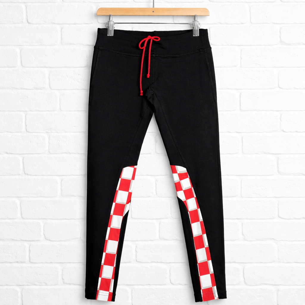 Pants / Leggings Croatia Black leggings with red and white checkered sides on a hanger against a white brick wall.