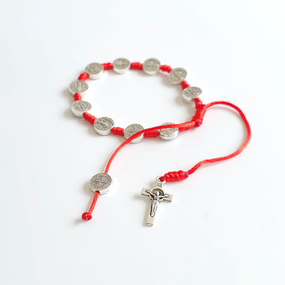 Saint Benedict Adjustable Bracelet with Cross (Red) Red cord bracelet with silver charms on a white background