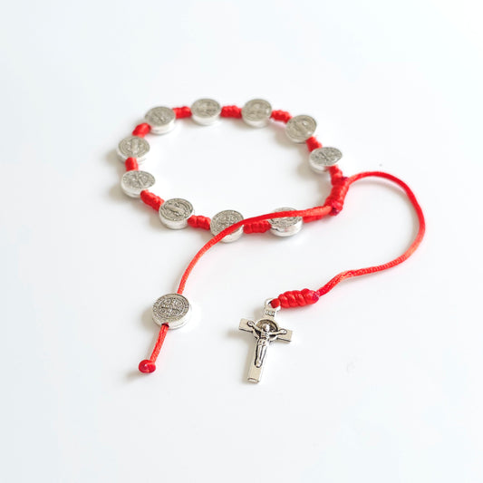 Saint Benedict Adjustable Bracelet with Cross (Red) Red cord bracelet with silver charms on a white background
