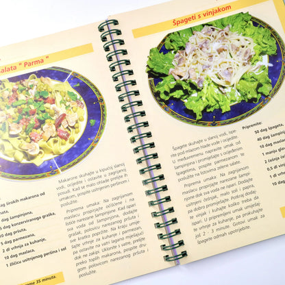 Salate - Prilog, Jela i Desert Open cookbook showing a page with spaghetti and broccoli dish and another dish on a blue plate.