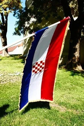Silk Flag Prvo Bijelo Polje 200x100 Croatian flag waving in the wind on a grassy area with trees in the background