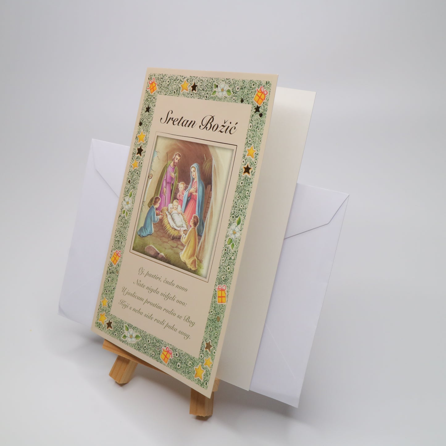 Sretan Božić Beige Christmas Greeting Card Decorative greeting card with religious illustration on a stand, featuring a white envelope.