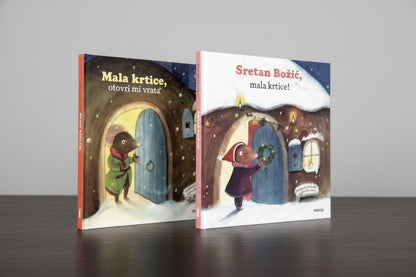 Sretan Božić, Mala Krtice! Two children's books titled 'Mala krtica, ovek mirnice' and 'Sretan Bozic, malakice!' with gift boxes on a wooden surface.