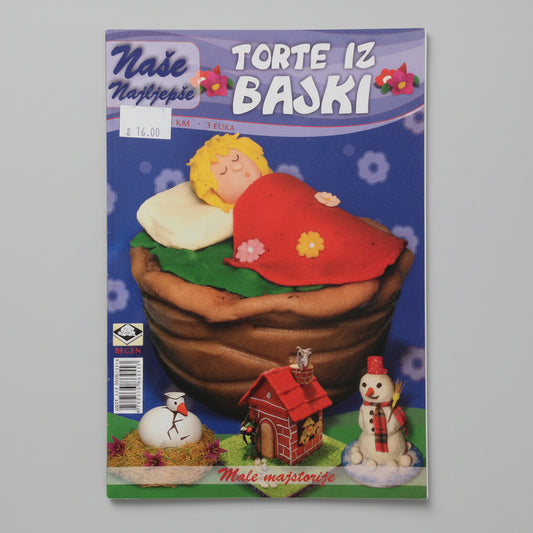 Naša Najljepša - Torte iz Bajki Magazine cover with a toy figure of a child in a basket, surrounded by small buildings and a snowman on a blue background.