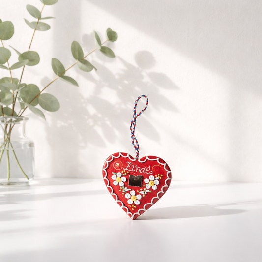 Traditional Souvenir Licitar (Licitarsko Srce) Decorative heart-shaped ornament with floral design and 'Zande' branding on a white surface with a plant in the background.