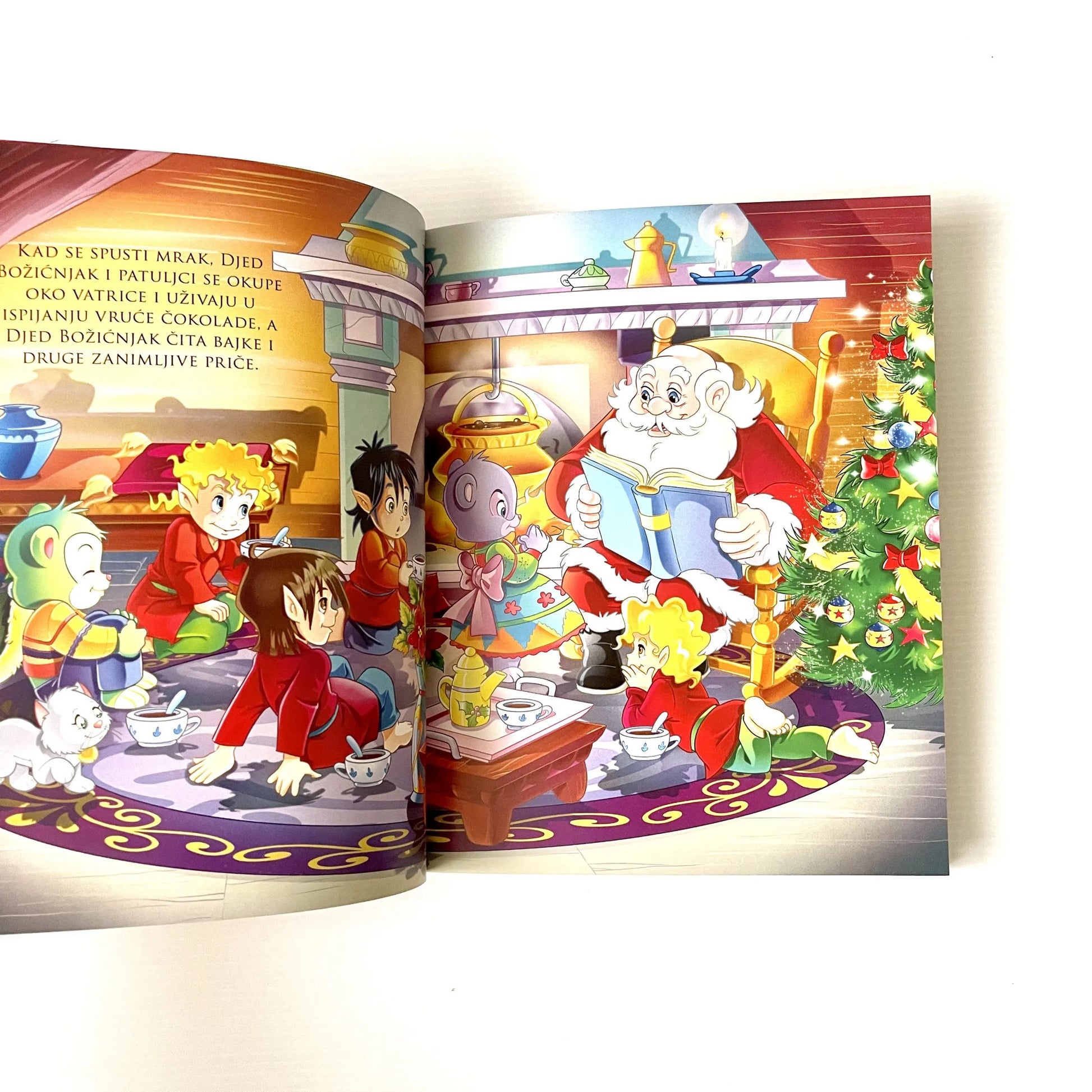 Čarobne priče - Božićne priče Open book with colorful illustrations of Santa Claus and children around a Christmas tree.